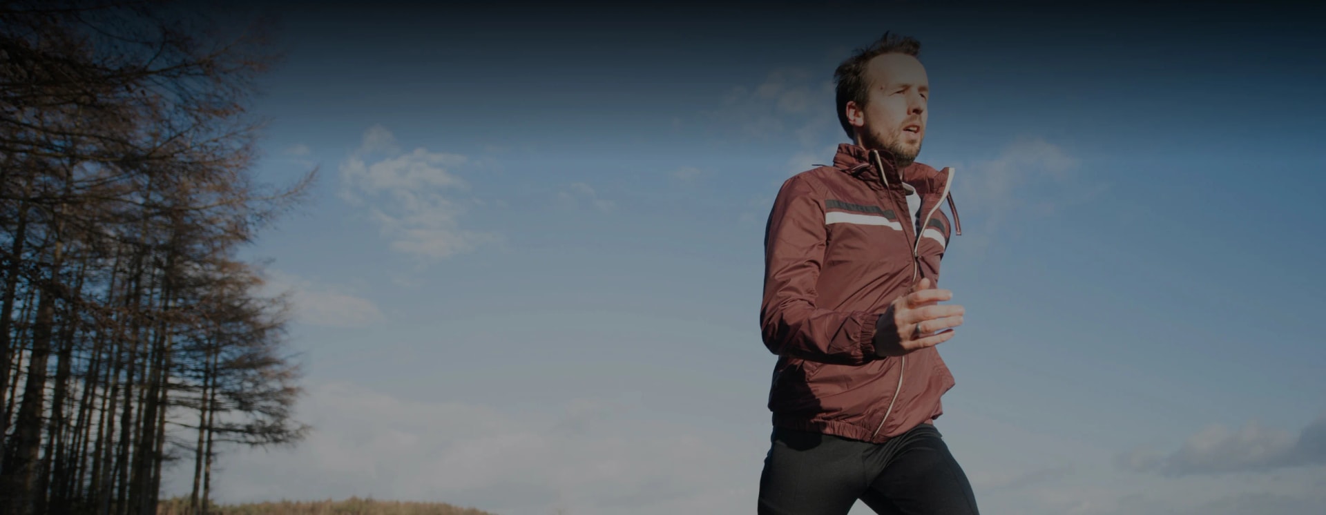 A person jogging by a wooded area
