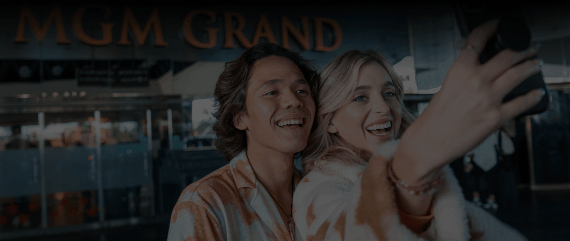 Two people taking a selfie in front of an MGM Grand sign