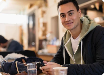 A person sitting at a table with a phone in their hands