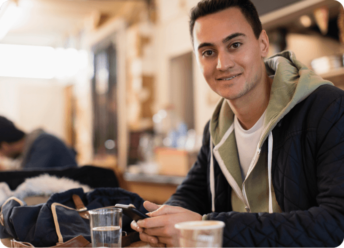 A person setting at a table with a phone in their hand