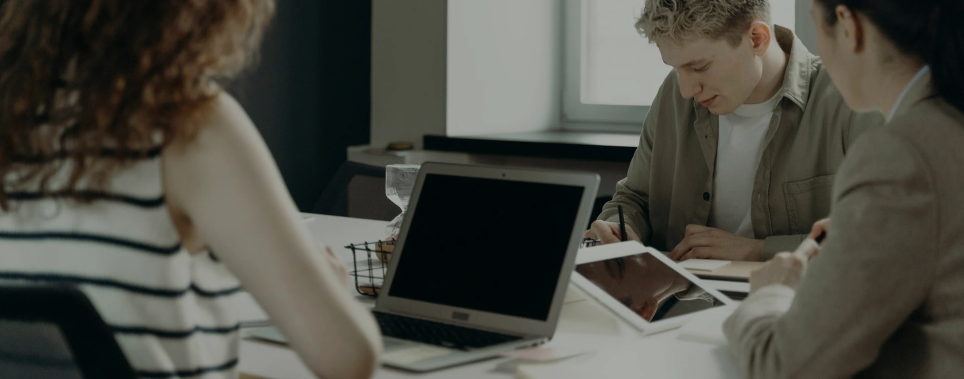 Three people sitting around a table with laptops