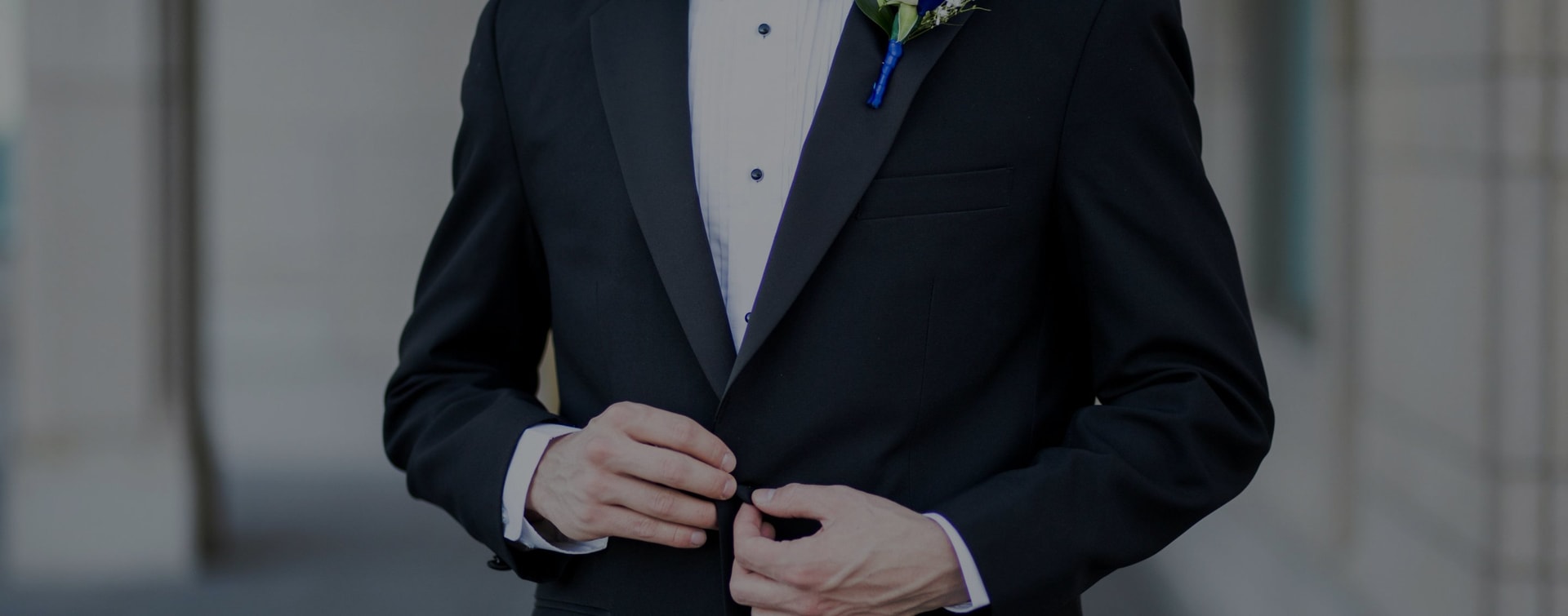 A person buttoning the top button of a tux