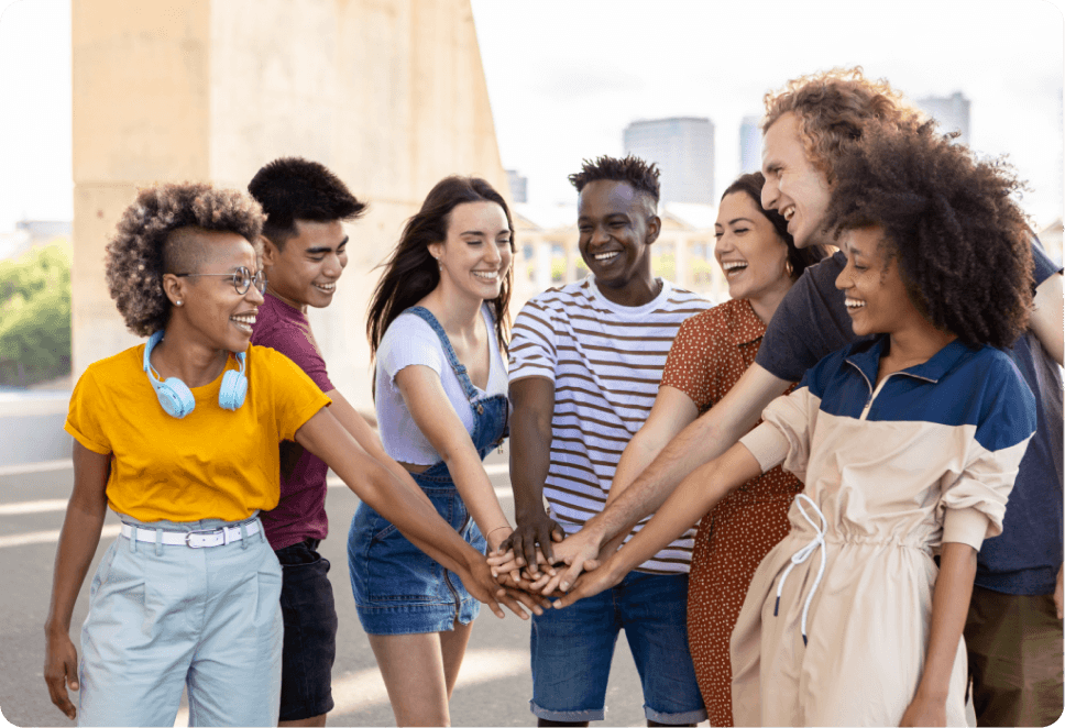 A group of 7 people with all of their hands in the middle of a circle